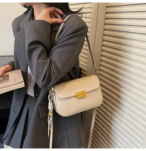 Chic cream leather crossbody bag with gold buckle on a model in gray blazer