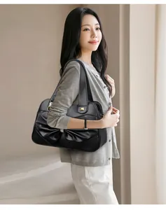 Detail of black leather handbag featuring a bow fold design with a silver diamond ornament