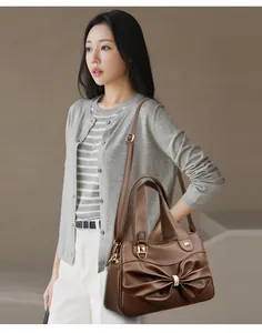 Brown leather handbag with bow and crystal detail shown on a model in a smart casual style