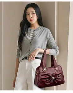 Close-up of elegant burgundy handbag featuring a large bow and rhinestone center detail