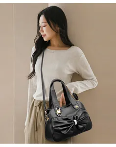 Detail of black faux leather tote with large bow and sparkling rhinestone buckle