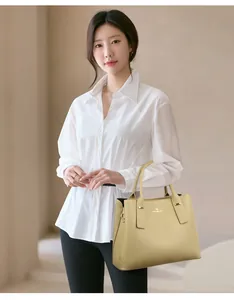 Close-up of beige leather bucket bag with golden kangaroo logo and metal hardware