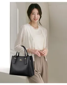 Close-up of black lychee grain leather handbag with golden kangaroo logo and double handles