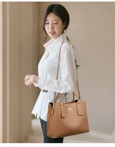 Close-up of brown pebbled leather handbag with gold kangaroo logo on white shirt