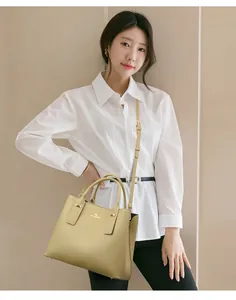 Detail of light green pebble leather tote bag featuring gold kangaroo logo and sturdy handles