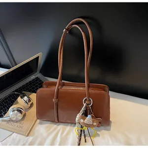 Brown oil wax leather tote bag with bear charm detail and extended shoulder strap