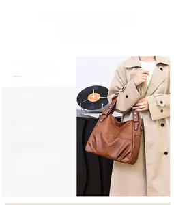 Detailed view of brown leather tote bag featuring pleated side design and metal hardware
