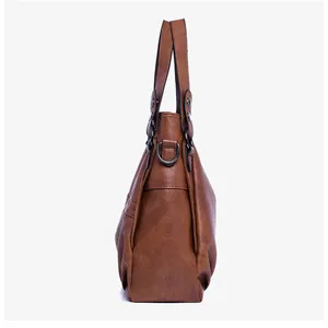 Detail view of brown textured leather tote showing side D-ring and metal rivets