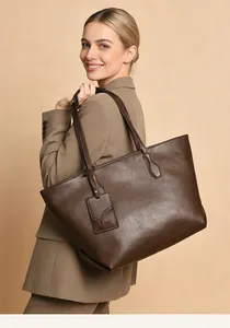 Detail of dark brown leather tote bag showing fine texture and branded bag charm