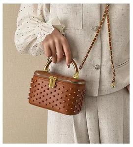 Brown vanity case bag with beads and metal handle held by model in elegant outfit