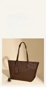 Detail of dark brown leather tote bag with elegant embossed tag and slim shoulder strap