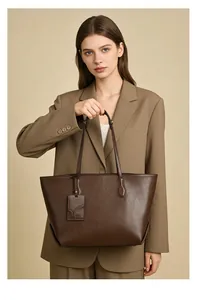 Detail of dark brown faux leather tote bag with tag shown on model in studio
