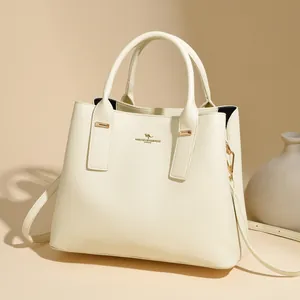 Minimalist beige pebble leather handbag with gold accents and detachable shoulder strap