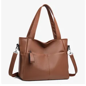 Dettaglio borsa shopper in pelle marrone con trama litchi, doppi manici e tasche laterali