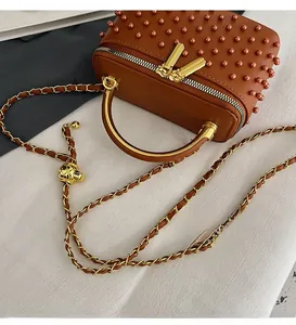 Detail of vanity box bag with brown bead embellishments and adjustable gold chain strap