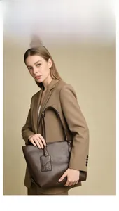 Detailed view of dark brown tote bag featuring premium leather texture and logo tag