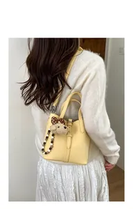 Detail of yellow bucket bag with lychee texture, plush bear pendant and beaded strap