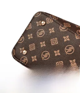 Détails de la base du sac en cuir marron avec des clous dorés et un motif monogramme
