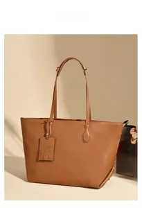 Detailed view of caramel brown tote bag with leather logo tag and pebble grain texture