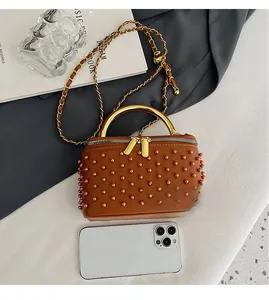 Mini brown box bag with pearls beside a smartphone showing practical small size