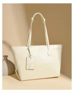 Close-up of cream soft leather tote bag with dual handles and matching hang tag detail