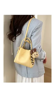 Detail of yellow lychee pattern bucket bag with brown bear charm shown on model