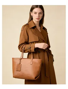 Classic caramel leather tote bag shown on shoulder with stylish trench coat for office look