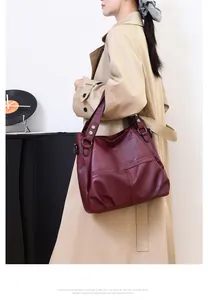 Close-up of deep burgundy pebble grain tote bag styled with a beige trench coat