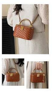 Close-up of brown vanity bag with pearl studs, gold handle and leather chain strap