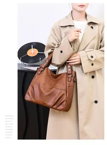 Detailed view of caramel brown faux leather shoulder bag with wide strap and metallic rings