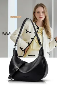 Detalle de bolso en cuero granulado negro con hebilla plateada y logotipo grabado