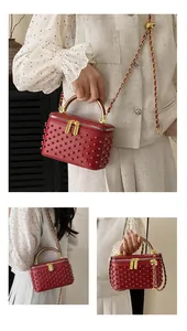 Detail of red box bag with matte leather, matching beads, and golden metal handle