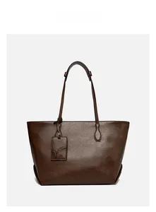 Detail of dark brown tote bag showing supple leather texture and embossed brand tag