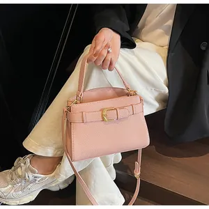 Détail du sac à main rose en cuir grainé avec boucle dorée porté par un mannequin
