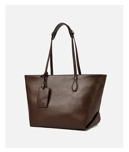 Detail of dark brown faux leather tote bag showing vintage texture and embossed brand tag