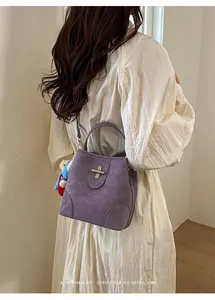 Detail of purple suede bucket bag with silver clasp, featuring a cute bear keychain charm