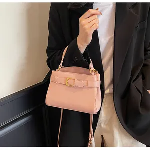 Détail d'un sac à main rose grainé avec boucle dorée et bandoulière réglable chic