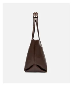Side view of dark brown tote bag with triangular structure and gold metal fasteners