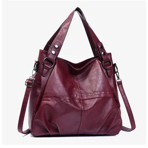 Close-up of deep burgundy crossbody bag featuring pebble leather texture and cross stitching