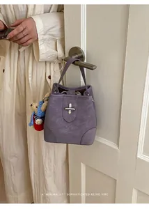 Close-up of retro purple bucket bag with silver metal lock and cute bear charm