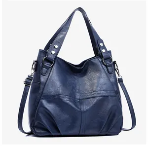Detail of navy blue leather tote bag with silver rivets and reinforced metal hardware