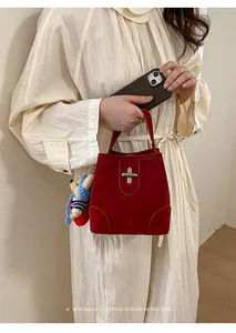 Detail of retro red bucket bag with silver cross-lock and plush teddy bear charm