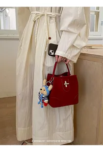 Detail view of burgundy retro bucket bag with gold clasp and cute teddy bear charm