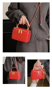 Detailed view of red box bag with pearl studs and golden metallic top handle and chain