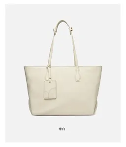 Close-up of cream white tote bag with textured soft leather and brand hangtag detail