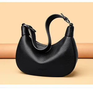 Detalle del bolso media luna de cuero negro con hebilla plateada ajustable en la correa