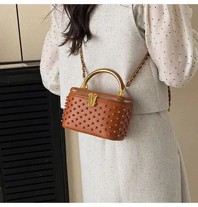 Brown box bag detail with stud embellishments and gold chain strap on model