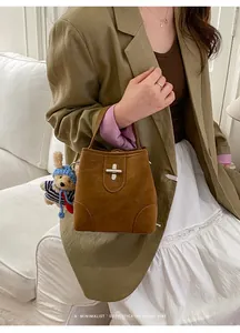 Detail of retro leather bucket bag featuring a teddy bear charm and metal twist lock closure