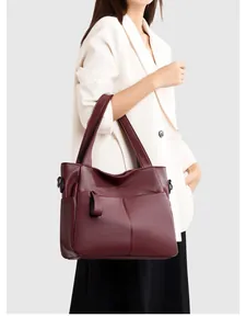 Dettaglio ravvicinato di una borsa tote in pelle bordeaux scuro con grana di litchi