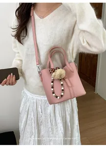 Pink lychee grain leather bucket bag with beaded charm and adjustable strap detail